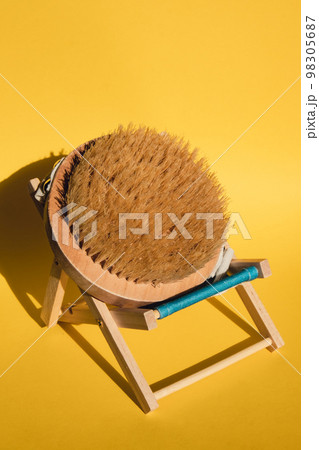Dry massage brush on beach chair with natural bristle, ecological cosmetics, home care. Bamboo Brush for dry anti-cellulite massage. Spa beauty concept Dry massage brush on beach chair with natural bristle, ecological cosmetics, home care. Bamboo Brush for dry anti-cellulite massage. Spa beauty concept 98305687