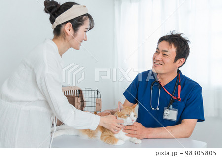 動物病院で獣医師に診察を受ける猫と飼い主のアジア人女性（ペット・相談・診察・診療） 98305805