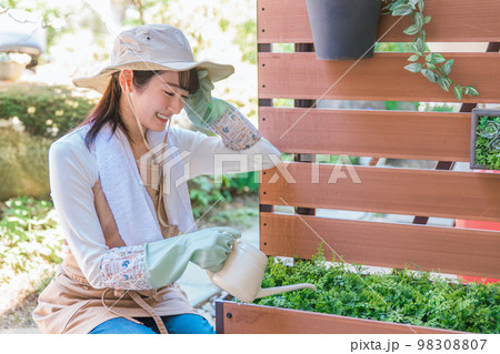 庭のガーデニングフェンスの花に水やりをする女性（園芸） 98308807
