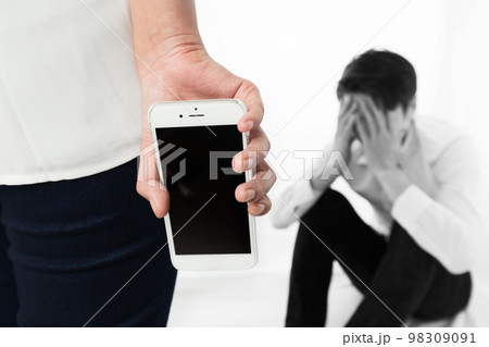 スマートフォンを持つ女性に頭を抱える男性 スマートフォンを持つ女性に頭を抱える男性 98309091