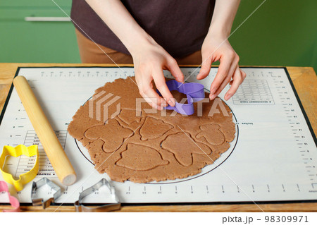 A woman prepares christmas homemade cookies on a silicone baking mat 98309971