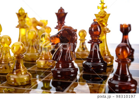Natural amber different chess pieces figures standing on brown stone board. Close up game concept competition, Classic Gambit Tournament of confrontation. Natural amber different chess pieces figures standing on brown stone board. Close up game concept competition, Classic Gambit Tournament of confrontation. 98310197