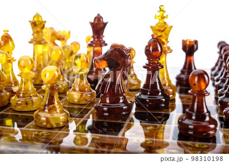Natural amber different chess pieces figures standing on brown stone board. Close up game concept competition, Classic Gambit Tournament of confrontation. Natural amber different chess pieces figures standing on brown stone board. Close up game concept competition, Classic Gambit Tournament of confrontation. 98310198