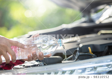 Man refill water to tank of car windshield wiper and checking up the engine before start the trip. Car maintenance or check up concept 98310552