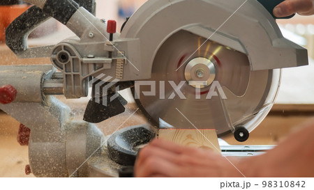 Master cuts the board with a circular saw in the workshop.  98310842