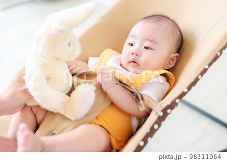 バウンサーに座る赤ちゃん ぬいぐるみであやす バウンサーに座る赤ちゃん ぬいぐるみであやす 98311064