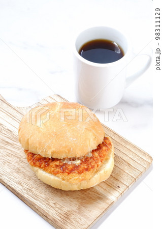 オーストリア発祥のロールパンのカイザーゼンメルにハムカツを挟んだサンドイッチとコーヒーの軽食をとる オーストリア発祥のロールパンのカイザーゼンメルにハムカツを挟んだサンドイッチとコーヒーの軽食をとる 98311129
