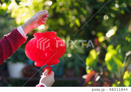 Asian Woman holding red Chinese new year lantern while decorated flat putting traditional pendant to the Chinese New Year Celebrations for good luck. chinese word means blessing. Asian Woman holding red Chinese new year lantern while decorated flat putting traditional pendant to the Chinese New Year Celebrations for good luck. chinese word means blessing. 98311844