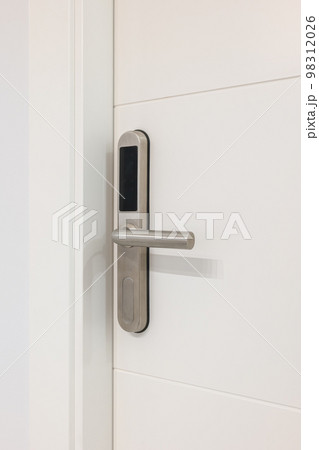 Door handle with plastic card with microchip or digital code. Closeup of an entrance white door with an electronic mortise lock. Door handle with plastic card with microchip or digital code. Closeup of an entrance white door with an electronic mortise lock. 98312026
