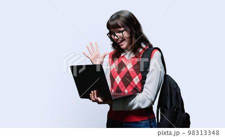 Smiling female student looking into laptop on light studio background 98313348