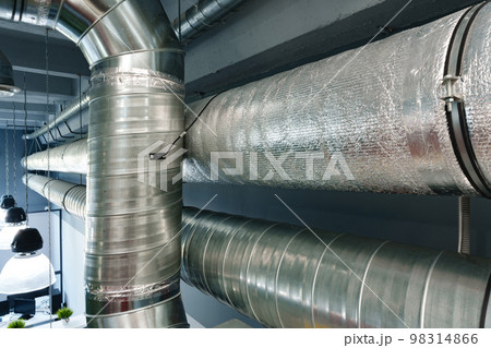 Silver ventilation pipes hanging from the ceiling inside the building 98314866