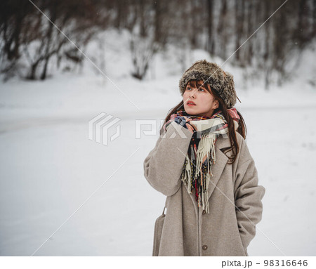 雪の積もった冬景色の中で無邪気に楽しむ女性 98316646