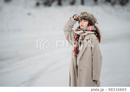 雪の積もった冬景色の中で無邪気に楽しむ女性 98316665