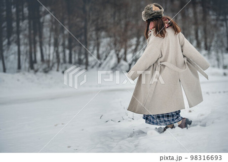 雪の積もった冬景色の中で無邪気に楽しむ女性 98316693