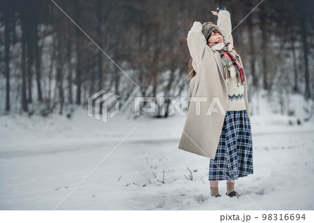 雪の積もった冬景色の中で無邪気に楽しむ女性 雪の積もった冬景色の中で無邪気に楽しむ女性 98316694