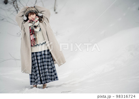 雪の積もった冬景色の中で無邪気に楽しむ女性 98316724