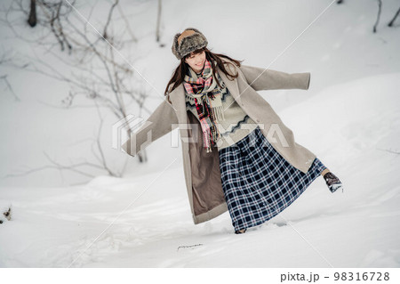 雪の積もった冬景色の中で無邪気に楽しむ女性 98316728