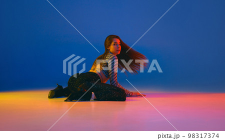 Warming up. Portrait of young girl dancing heels dance in stylish clothes over blue background in neon light. Concept of modern dance style 98317374
