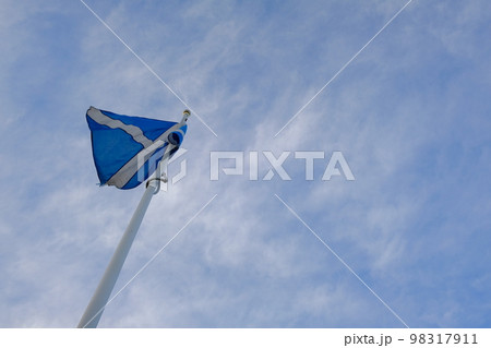 青空の下でなびくスコットランドの国旗 98317911
