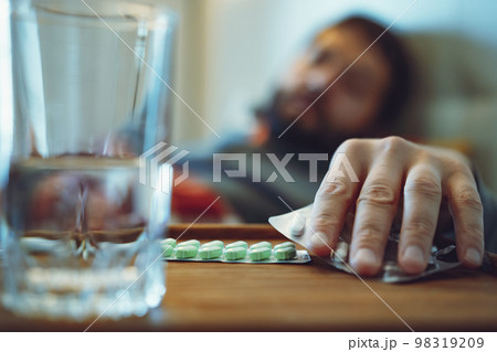 sick man staying in bed taking a pill. closeup view of hand 98319209