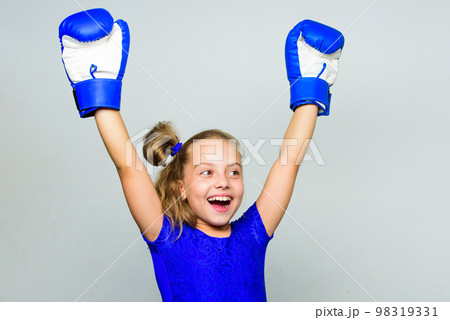 Girl child happy winner with boxing gloves posing on grey background. Feminist movement. She feels as winner. Upbringing for leadership and winner. Strong child proud winner boxing competition Girl child happy winner with boxing gloves posing on grey background. Feminist movement. She feels as winner. Upbringing for leadership and winner. Strong child proud winner boxing competition 98319331