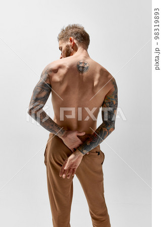 Back view. Young blonde man with beard and moustache posing shirtless. Perfect muscular body shape. Tattoo body art. Concept of fashion, style, body aesthetics, beauty, men's health 98319893