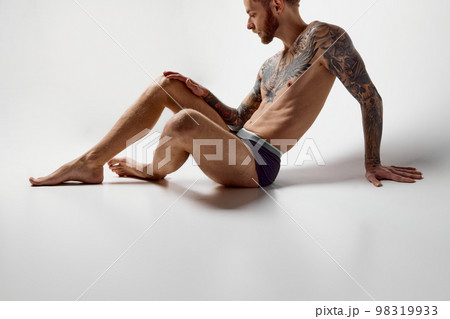 Portrait of muscular male fashion model posing isolated over grey studio background. Masculinity. Concept of men's health, beauty, body and skin care, fitness. Body art Portrait of muscular male fashion model posing isolated over grey studio background. Masculinity. Concept of men's health, beauty, body and skin care, fitness. Body art 98319933
