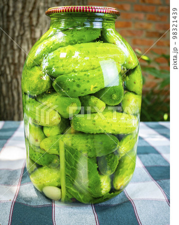 Canned cucumbers in a glass jar on the table. 98321439