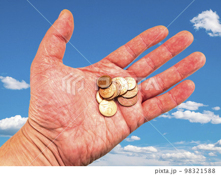 Hand with money coins on a background of blue sky. 98321588