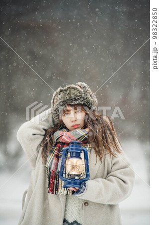 雪降る中ランタンを持ち楽しそうにする女性 雪降る中ランタンを持ち楽しそうにする女性 98322850