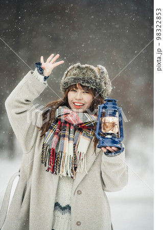 雪降る中ランタンを持ち楽しそうにする女性 雪降る中ランタンを持ち楽しそうにする女性 98322853