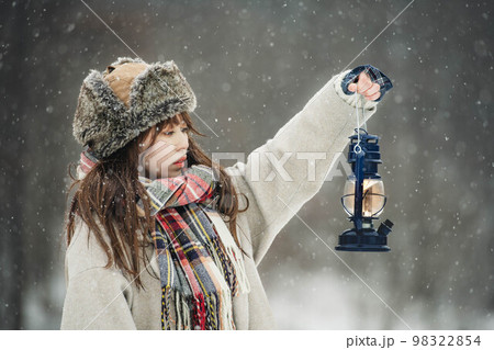雪降る中ランタンを持ち楽しそうにする女性 雪降る中ランタンを持ち楽しそうにする女性 98322854