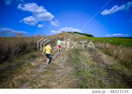 Two boys of school age are walking and admiring the view of the mountains, children in bright clothes. Travel with children summer concept Two boys of school age are walking and admiring the view of the mountains, children in bright clothes. Travel with children summer concept 98323134