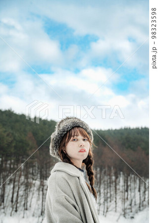 青空の雪景色の中でアンニュウイな表情をする女性 98323598