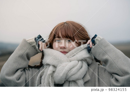 見通しの良い河川敷で散歩しているマフラーを巻いた女性 98324155