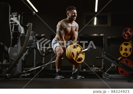 Power. Portrait of young muscular man training shirtless in gym indoors. Lifting barbell exercise. Relief body shape. Concept of sport, workout, strength Power. Portrait of young muscular man training shirtless in gym indoors. Lifting barbell exercise. Relief body shape. Concept of sport, workout, strength 98324925