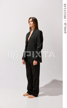 Portrait of young beautiful girl posing black classic suit over grey studio background. Style. Concept of body and skin care, fitness 98325148