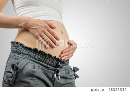 Young pregnant woman cradling her belly 98325332