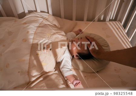 パパに撫でてもらって赤ちゃんが夜に寝かしつけられて寝ている姿 98325548