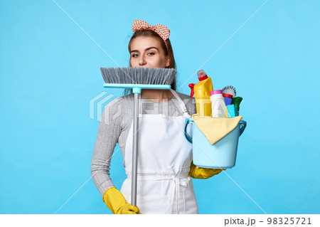 woman in gloves holding bucket of detergents and broom 98325721