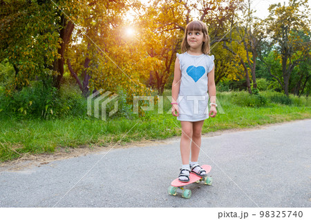 Cute girl riding a skateboard in the park at sunset. Healthy lifestyle Cute girl riding a skateboard in the park at sunset. Healthy lifestyle 98325740