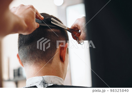 hairdresser does hairstyle and style with scissors 98325840