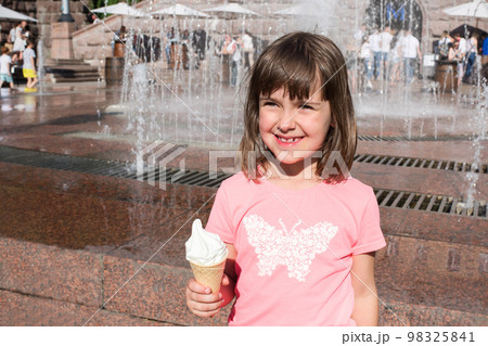 A portrait of a happy little girl with ice cream in hands on a background of fountains A portrait of a happy little girl with ice cream in hands on a background of fountains 98325841