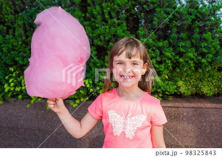 A open portrait of a cute smiling girl with cotton candy. Sweets, caramel A open portrait of a cute smiling girl with cotton candy. Sweets, caramel 98325843