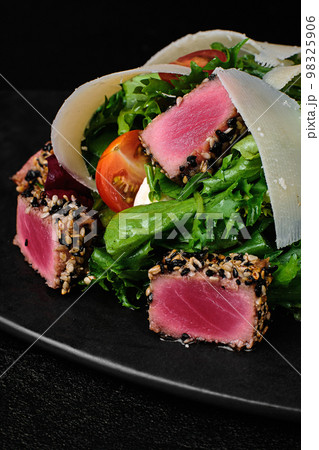 Tuna salad with parmesan on black plate on black concrete background Tuna salad with parmesan on black plate on black concrete background 98325906
