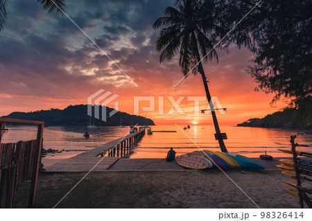 Beautiful sunset over tropical sea and wooden bridge, sightseeing boat and tourist enjoying in Koh Kood beach 98326414