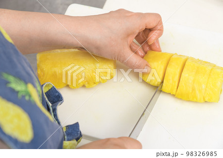 【皮削ぎの終わったパイナップルを切っていく】 98326985