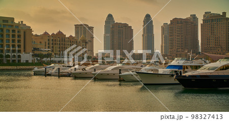 Porto Arabia Marina in The pearl , Doha, Qatar sunset shot showing luxurious yachts and boats docked at the marina with residential buildings in background. Porto Arabia Marina in The pearl , Doha, Qatar sunset shot showing luxurious yachts and boats docked at the marina with residential buildings in background. 98327413
