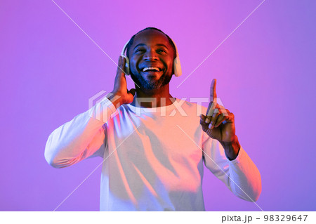 Joyful black man listening to music and smiling 98329647