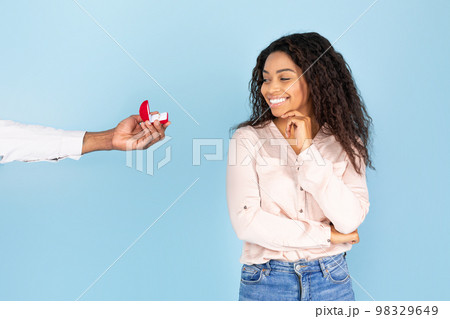 Marriage proposal. Man giving ring in box to happy black lady isolated on blue background, studio shot, copy space 98329649